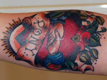 Tatuaje de un corazón, dos brazos dándose la mano y flores