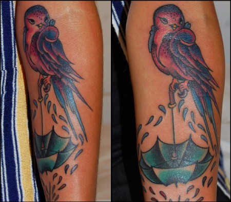 Tatuaje de un pájaro encima de un paraguas