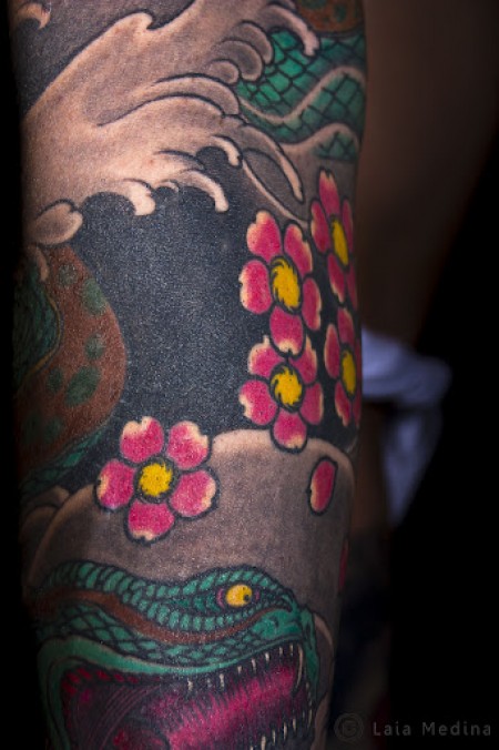 Tatuajes de una serpiente japonesa entre olas y flores