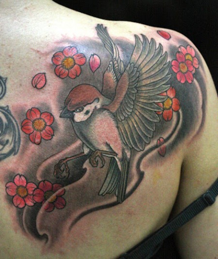 Tatuaje de un gorrión volando entre flores
