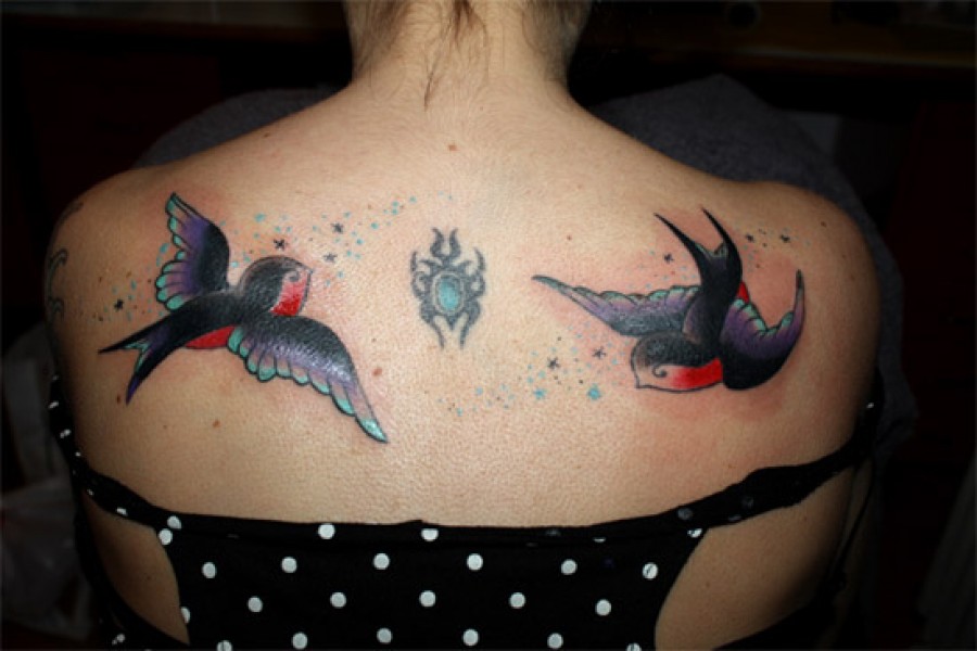 Tatuaje de dos golondrinas volando por la espalda