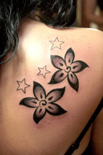 Tatuaje de flores y estrellas en la espalda de una chica