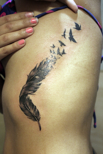 Tatuaje de una pluma descomponiéndose en pájaros