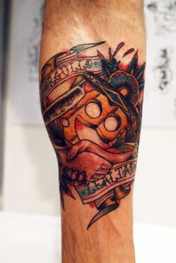 Tatuaje de una navaja de afeitar un puño americano, unas manos abrazandose y una etiqueta