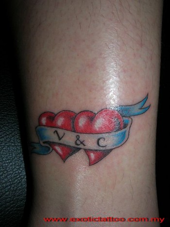 Tatuaje de dos corazones unidos por una etiqueta con dos iniciales