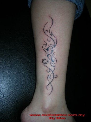 Tatuaje de una inicial rodeada de lineas finas en la pierna