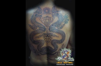 Tatuaje de dragones tailandeses en la espalda con flores de loto