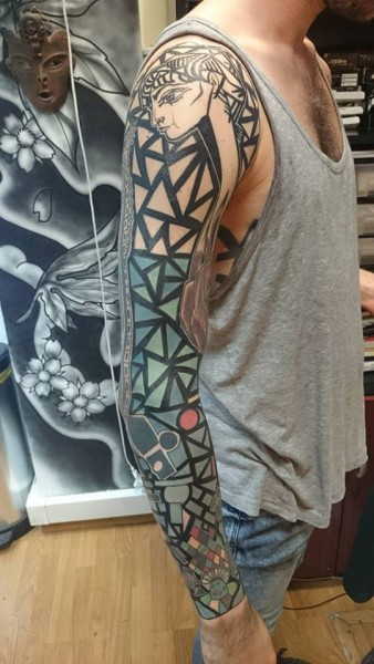 Manga de tatuaje en el brazo con triángulos y una cara egipcia