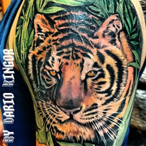 Tatuaje de un tigre saliendo de entre las plantas