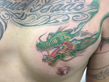 Tatuaje de una cabeza de dragon a color en el pecho de un hombre