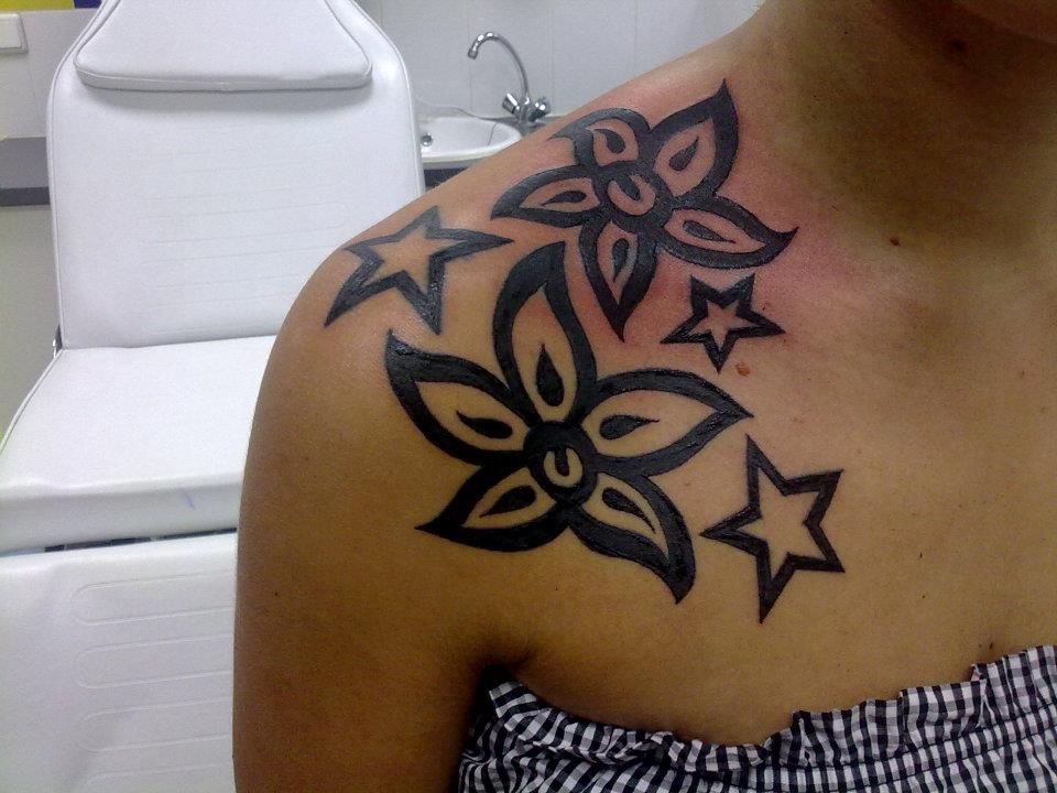 Tatuajes de estrellas y flores en el hombro de una chica