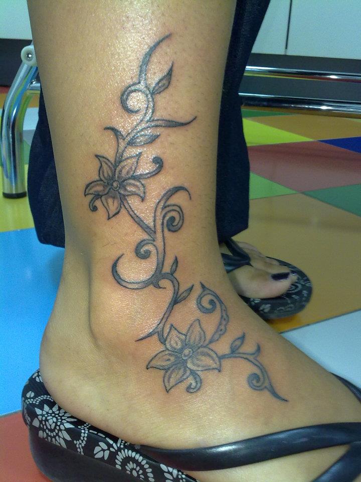 Tatuaje de una enredadera con flores en el tobillo