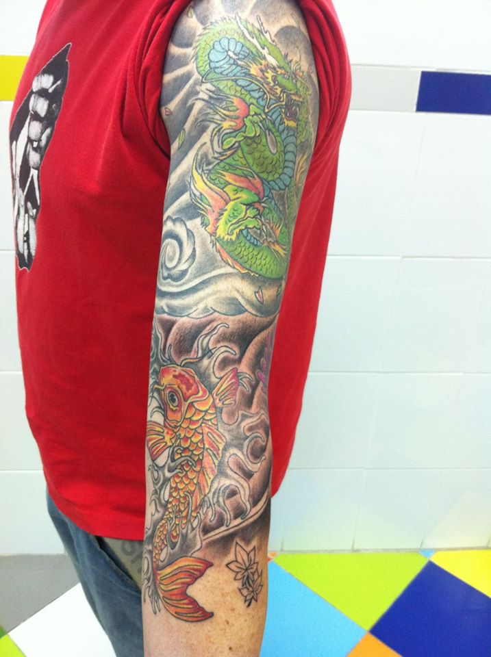 Brazo tatuado al estilo japonés con un dragón y una carpa