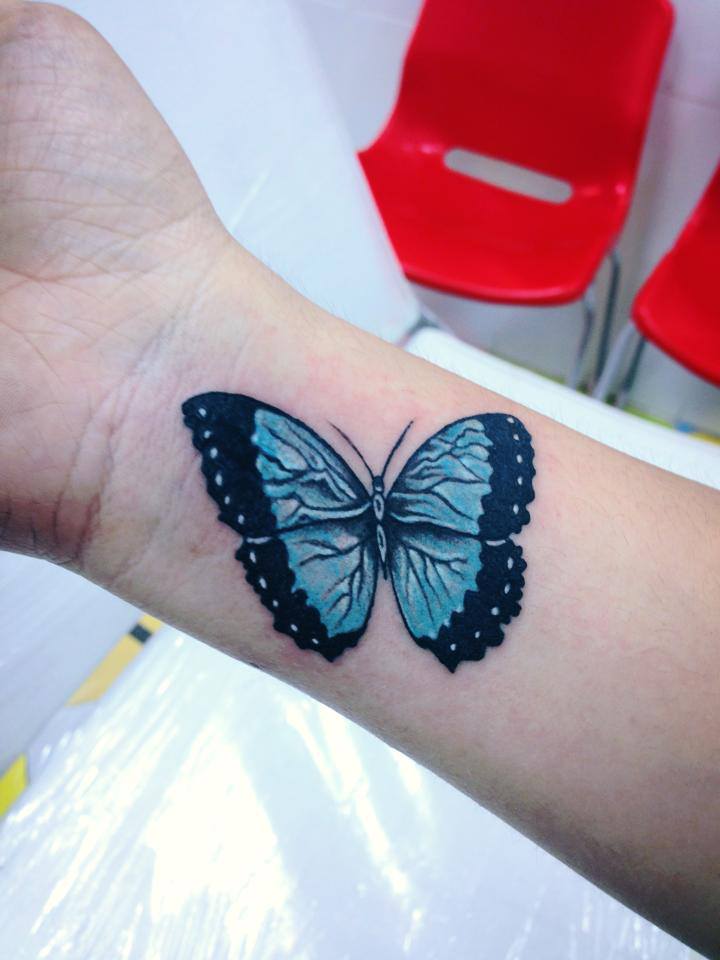 Mariposa a color tatuada en la muñeca