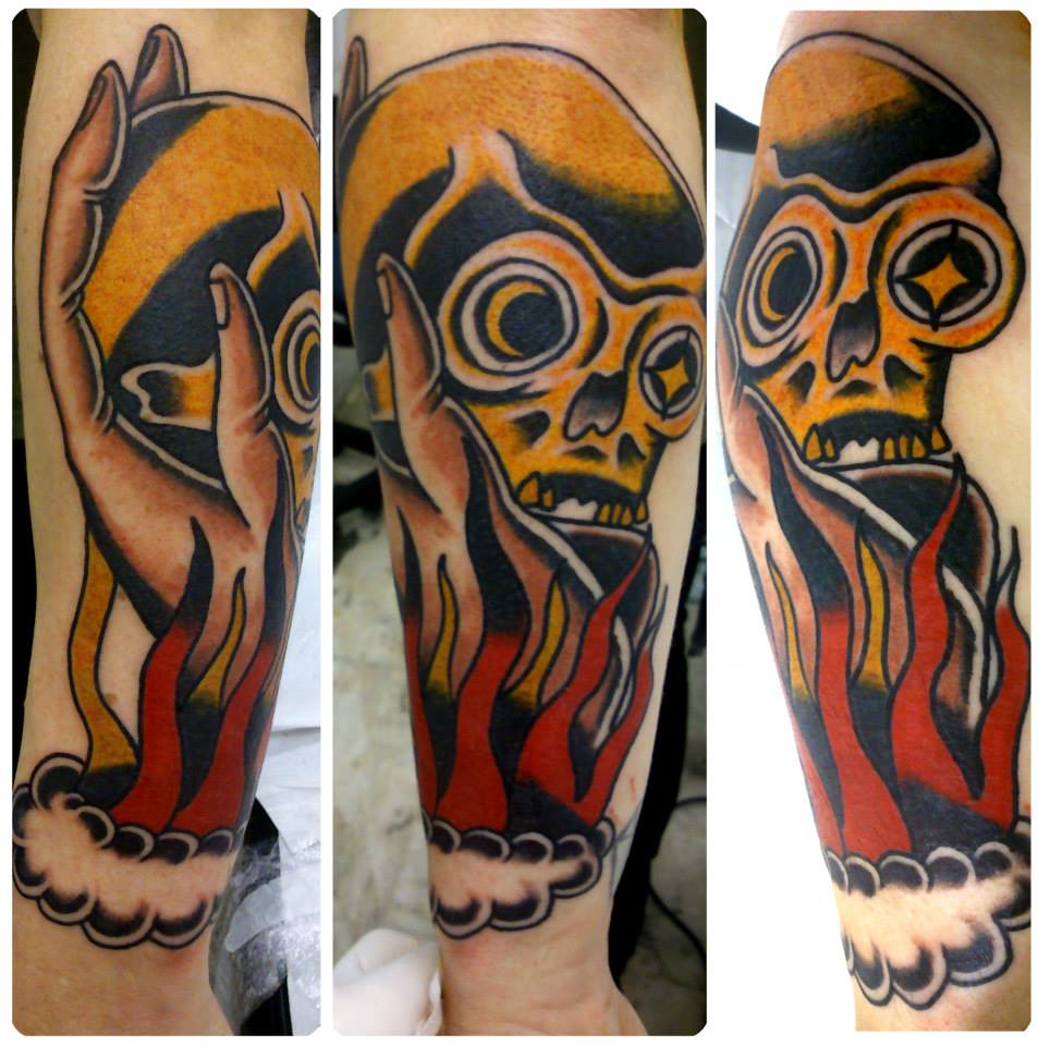 Tatuaje de una mano saliendo del fuego y aguantando una calavera