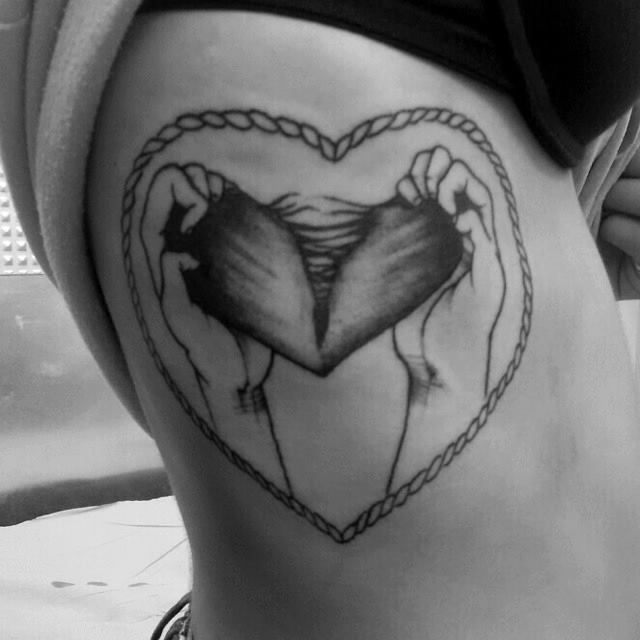 Tatuaje de un corazón desgarrado dentro de un marco de cuerdas