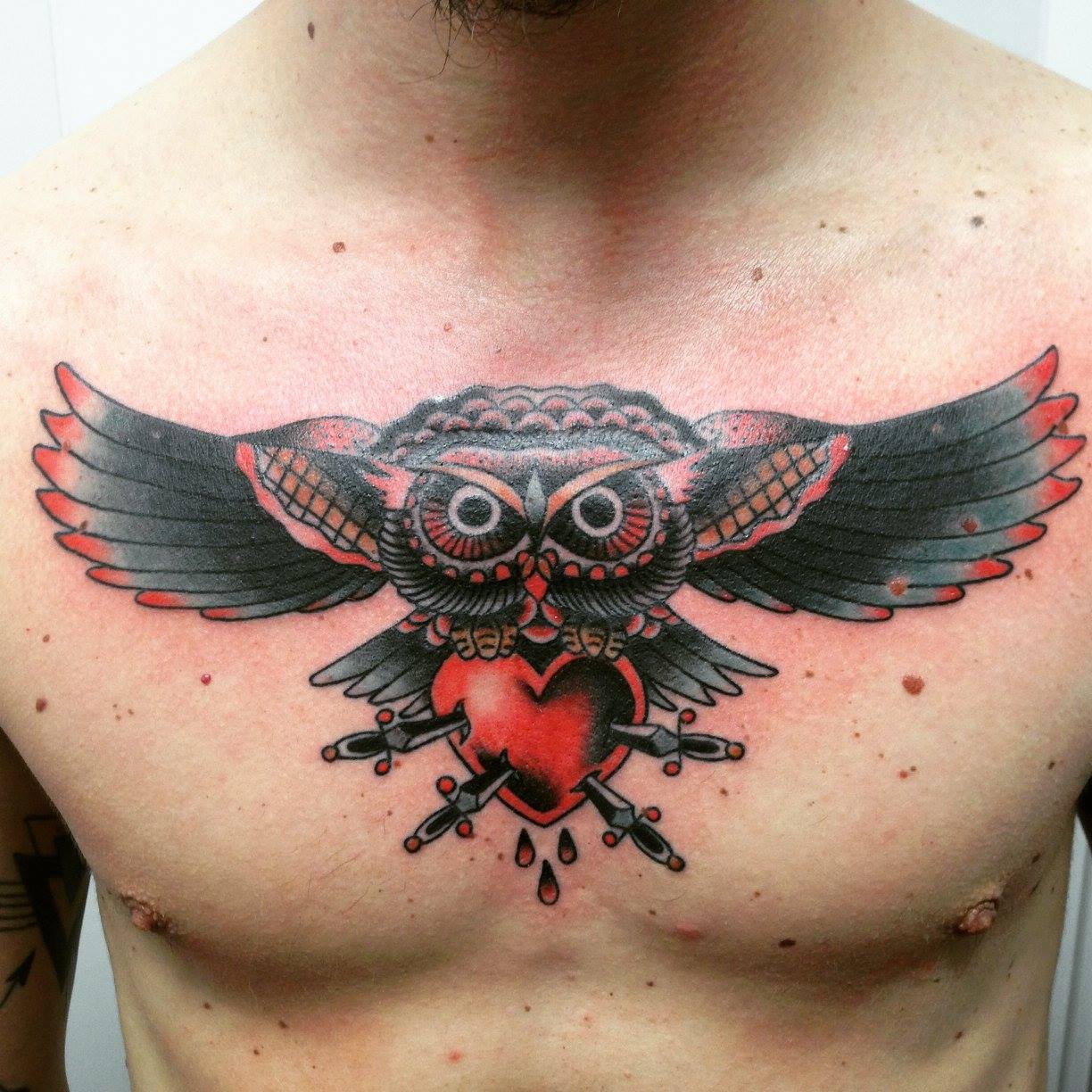 Tatuaje a color de un búho transportando un corazón atravesado por espadas