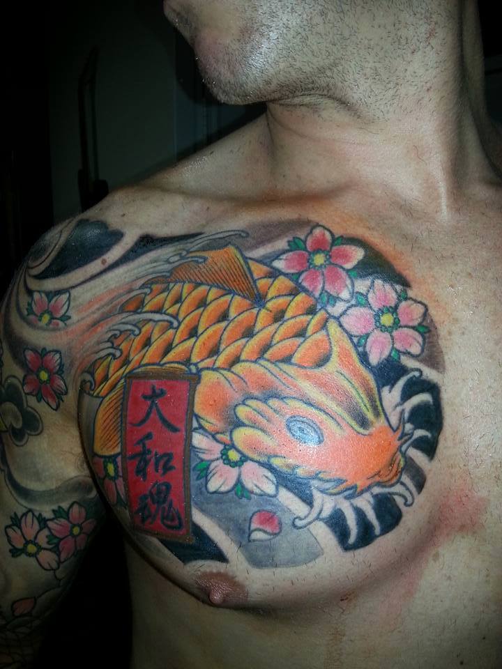 Tatuaje de un koi en el pecho de un hombre con un cartel en japonés