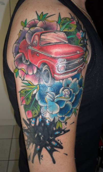 Tattoo de un coche, entre flores y una mancha de tinta