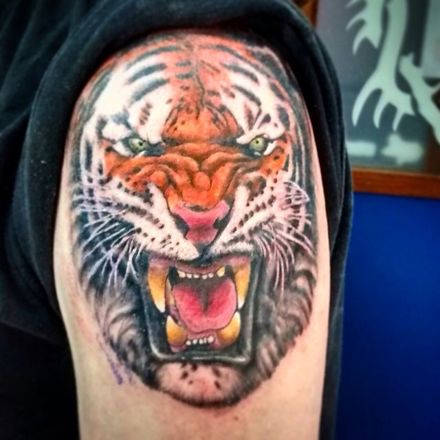 Tattoo a color de una cara de tigre en el hombro