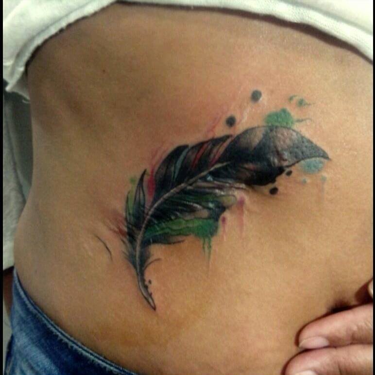 Color tattoo de una pluma con unas manchas de pintura