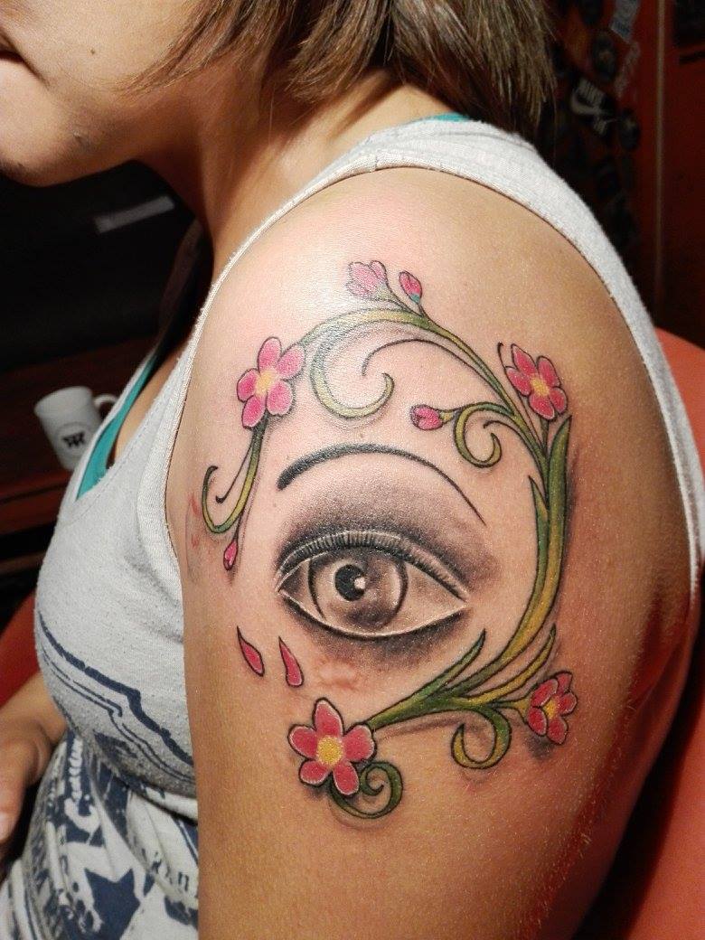Tattoo de un ojo rodeado de un circulo de plantas