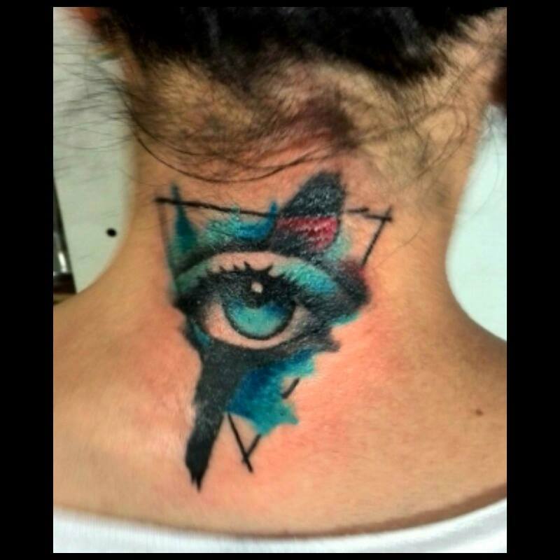 Tattoo de un ojo dentro de un triángulo, con manchas de pintura