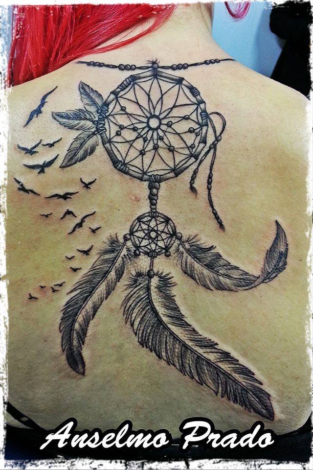 Tattoo de un atrapasueños colgado de la nuca, con pájaros volando