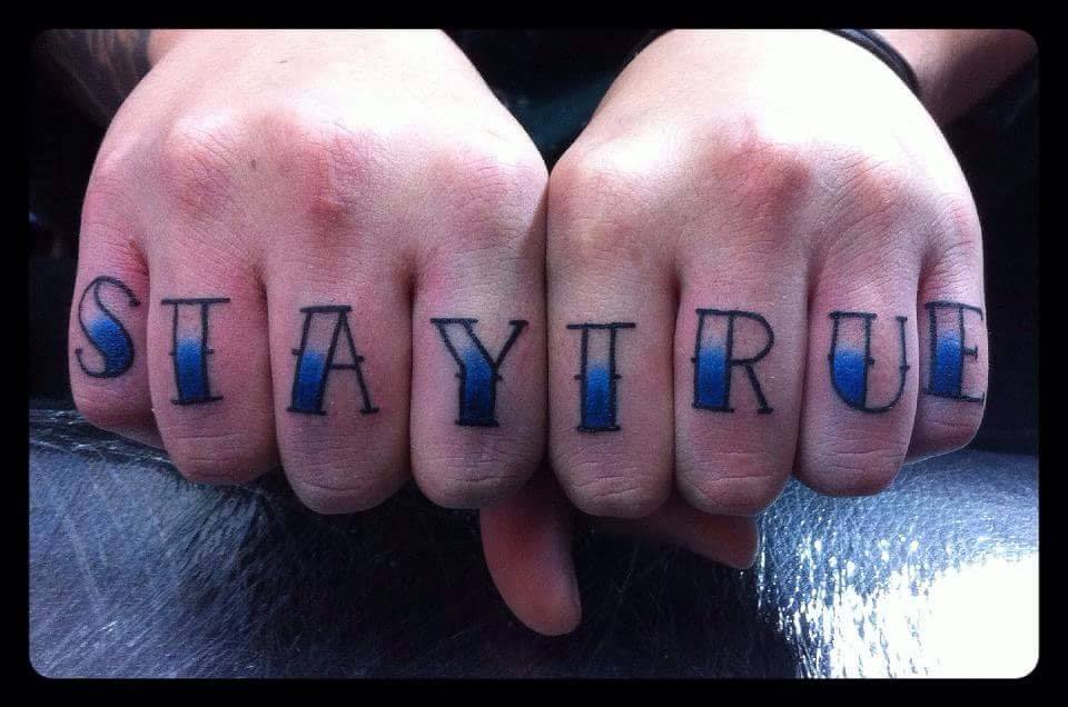 Tatuaje de la palabra STAY TRUE en los dedos