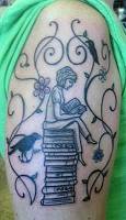 Tatuaje de una chica leyendo sobre una montaña de libros