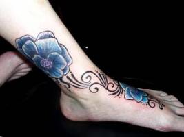 Tatuaje para mujeres. Tatuaje de unas flores en el pie y tobillo