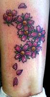 Tatuajes de unas flores y algunos pétalos caídos en el tobillo