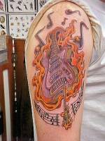 Tatuaje de guitarra entre llamas y notas musicales en el brazo