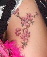 Tatuaje para mujeres, ramas con flores para el muslo