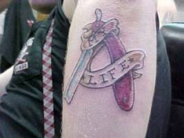 Tatuaje de una navaja de barbero en el brazo