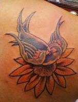 Tatuaje de pájaro encima de una flor
