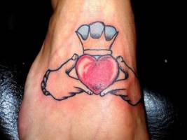 Tattoo de corazón con corona sujetado por unas manos