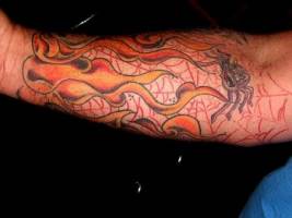 Tatuaje de un brazalete de fuego para el antebrazo con unas telarañas 