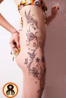 Tatuaje para mujeres de flores plantas y estrellas subiendo por el lateral