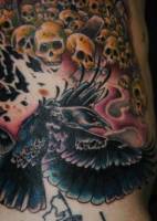 Tatuaje de un cuervo con una infinidad de cráneos de calaveras