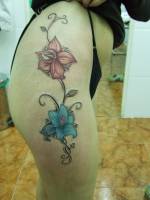 Tatuaje de dos grandes flores en el muslo de una mujer