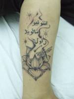 Tatuaje de una flor con unas letras árabes