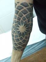 Tatuaje de un rosetón en el brazo y codo