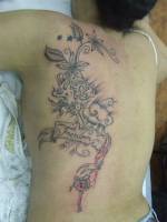 Tatuaje de flores, dados, delfines y cerrojos en la espalda