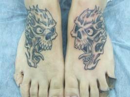 Tatuaje de dos calaveras una en cada pie, mirandose
