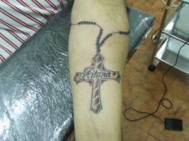 Tatuaje de un brazalete con una cruz colgando