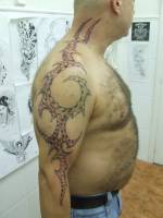 Tatuaje de un tribal en el brazo y cuello