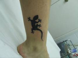 Tatuaje de una lagartija subiendo por la pierna