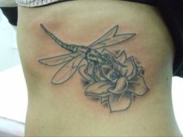 Tatuaje de una libélula volando hacia una flor