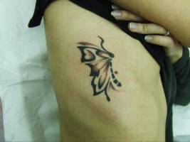 Tatuaje de una mariposa en el lateral de una mujer